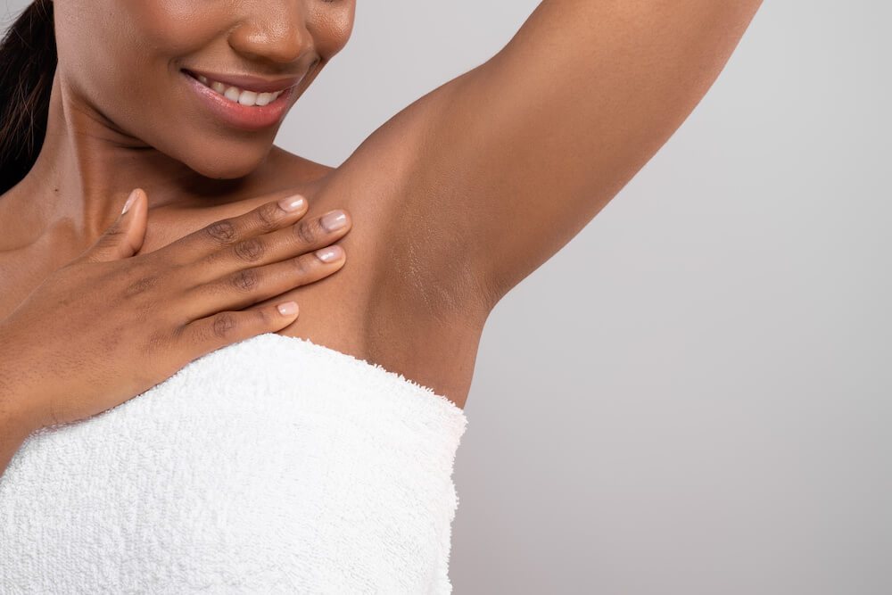 Woman looking at her armpit not sweating after MiraDry treatment in New York